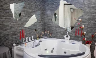 a bathroom with a large white bathtub surrounded by mirrors and red candles , creating a romantic atmosphere at The Lux