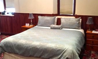 a neatly made bed with a gray comforter and matching pillows is shown in a bedroom at Clare Valley Cabins
