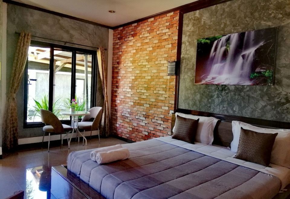 a large bed with a gray comforter is in a room with brick walls and a glass table at Khun Naparn Resort