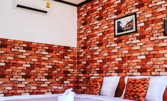a bed with a brick wall behind it and two pillows on the bottom bed at Khun Naparn Resort
