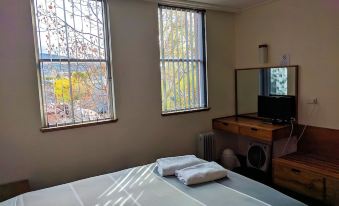 a bed with a white blanket and two folded white towels on it , next to a window with a view at Prince of Wales Hotel