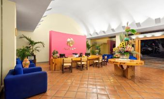 a large room with a pink wall and several tables , chairs , and a potted plant at Hotel Rancho San Diego Grand Spa Resort