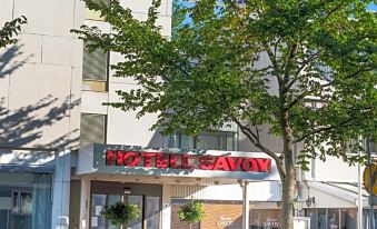 "a modern building with a red sign reading "" mayon "" and a tree in front of it" at Hotel Savoy