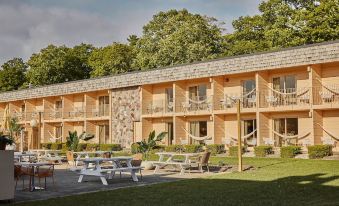 a large building with multiple balconies and a stone wall , surrounded by trees and grass at The June Motel