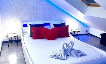 a white bed with a red and blue pillow is situated in a room with sloped ceilings at Lovely