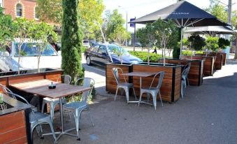 an outdoor dining area with several tables and chairs , as well as a car parked nearby at Middle Park Hotel