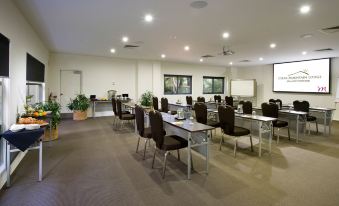 a large conference room with rows of chairs arranged in a semicircle , and a podium at the front of the room at Mercure Clear Mountain Lodge