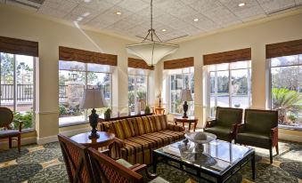 a spacious living room with multiple couches and chairs arranged around a coffee table , creating a comfortable seating area at Hilton Garden Inn Tampa/Riverview/Brandon