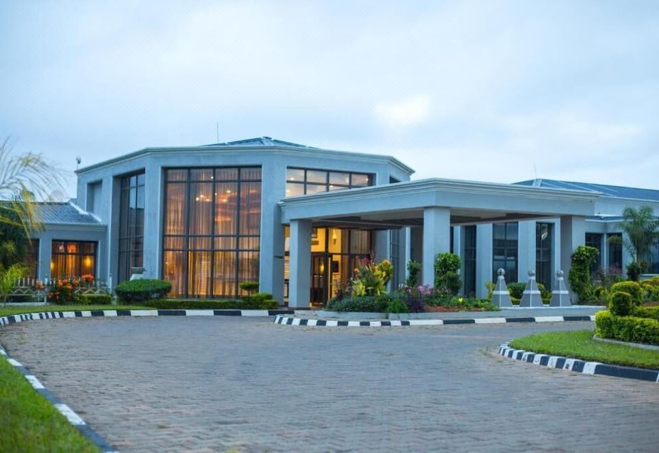 a large building with a parking lot in front of it , surrounded by grass and trees at Grand Palace Hotel Mzuzu