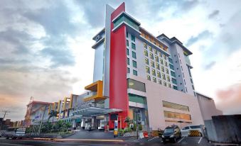 a tall , modern hotel building with a red and white facade , located on a city street at Grand Artos Hotel & Convention