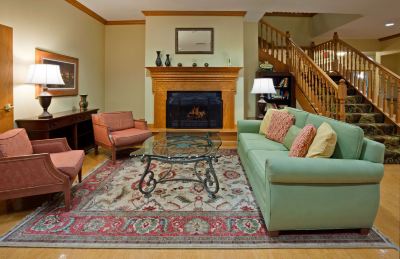 a cozy living room with a fireplace , two couches , and a staircase leading to the second floor at Country Inn & Suites by Radisson, Watertown, SD