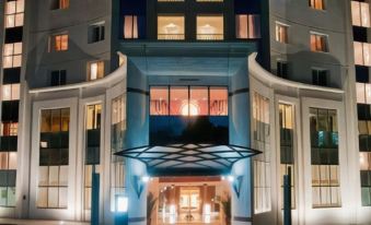 a modern hotel building with multiple floors and balconies , illuminated at night , and a sign above the entrance at Tunis Grand Hotel