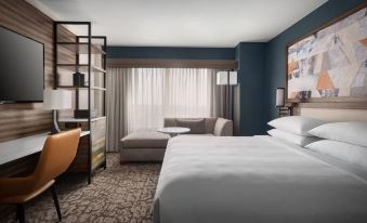 a modern hotel room with a large bed , couch , and office area , along with other furniture and amenities at Marriott Boston Quincy