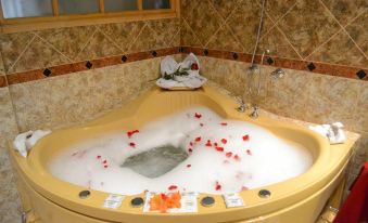 a large bathtub filled with water and filled with bubbles , surrounded by various items such as towels , cups , and bottles at Hotel Midori