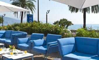 a blue lounge area with several blue chairs and a view of the ocean in the background at Hotel Victoria