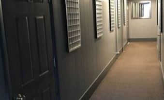 a long , dimly lit hallway with several doors on both sides and windows on the right side at Lofts on Main