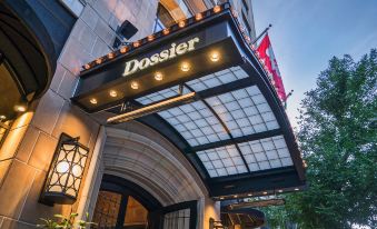 a hotel entrance with a large sign above it , illuminated by the sun 's rays at Dossier