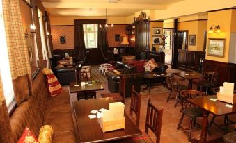 a cozy bar with wooden furniture , including tables and chairs , and a bar area filled with various items at The Red Lion