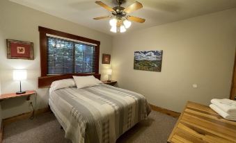 a cozy bedroom with a wooden bed , a ceiling fan , and a window overlooking the outdoors at Opossum Creek Retreat