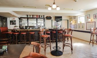 a bar area with several chairs and stools , along with bottles and glasses on the counter at Hotel Astor