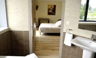 a bedroom with a bed , nightstand , and sink is visible through an open doorway into another room at Le Grand Hotel