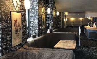a bar with several couches and chairs , some of which are covered in gray fabric at The George Hotel