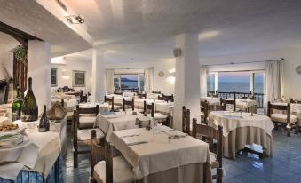a large dining room with white tablecloths and chairs , creating a warm and inviting atmosphere at Club Hotel Baja Sardinia