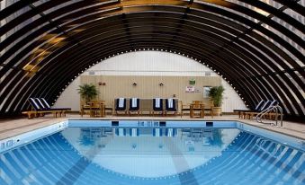 a large indoor swimming pool surrounded by lounge chairs , where people are relaxing and enjoying their time at Oheka Castle Hotel & Estate