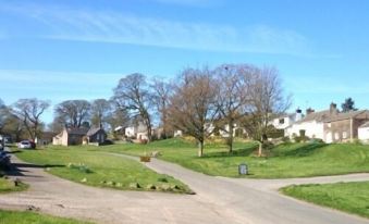 a rural scene with a dirt road leading to a house , surrounded by trees and grass at The Punchbowl Inn