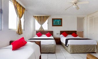 A bedroom with two beds, each adorned with red pillows, accompanied by a side table at Capital O Farallon Inn