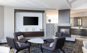 a modern living room with a large flat - screen tv mounted on the wall , surrounded by comfortable chairs and a fireplace at Residence Inn Largo Medical Center Drive