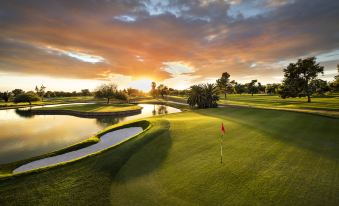 a golf course with a lake in the background , and a red flag on the green at The Wigwam