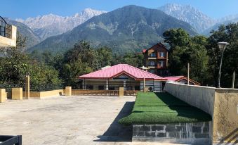 a red - roofed building with a green lawn in front of it , surrounded by mountains in the background at The Sojourn