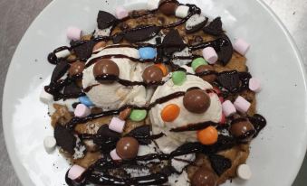 a white plate with a scoop of ice cream topped with various toppings , such as chocolate chips , nuts , and m & m 's at North Devon Resort