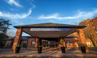 the entrance to a hotel or resort with a large sign above the door and a blue sky in the background at DoubleTree by Hilton Manchester Airport