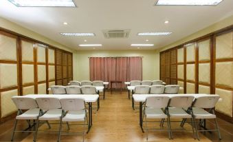 a conference room with rows of chairs arranged in a semicircle , and a projector on the wall at La Luz Beach Resort