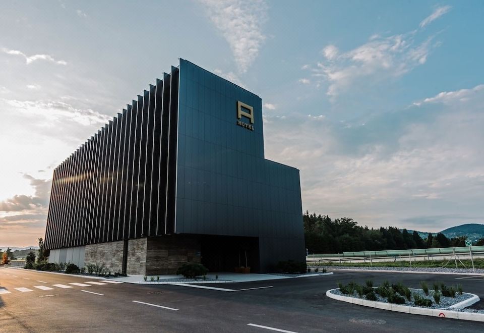 a modern building with a black and gold exterior , surrounded by trees and a clear sky at Hotel A