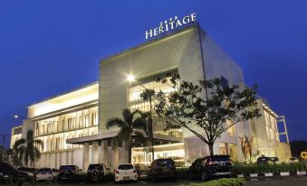 a large hotel building surrounded by trees and cars parked in front of it at Java Heritage Hotel Purwokerto