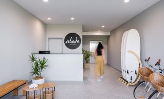 "a modern office interior with a white reception desk , wooden coffee table , and potted plants , as well as a black "" abade "" logo" at Abode Malua Bay