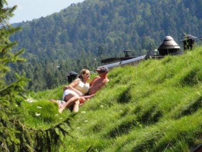 a couple is enjoying a day on a grassy hill , with the man leaning against the woman and the woman holding the man 's hand at Troll