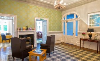 a living room with green walls , a fireplace , and two chairs arranged around a coffee table at Balcary House Hotel