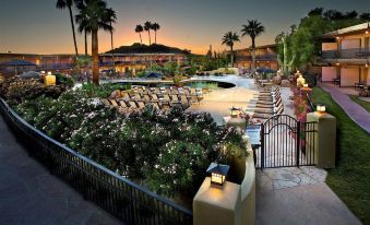 a resort with a pool surrounded by lounge chairs , trees , and a fence , as well as a hotel in the background at Civana Wellness Resort & Spa