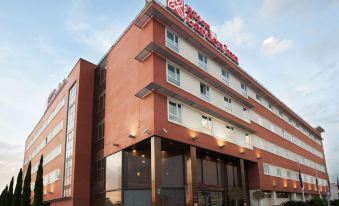 "a large red brick building with a sign that reads "" days inn "" prominently displayed on the front" at Hilton Garden Inn Malaga