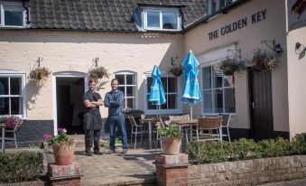 a man and a woman are standing outside of a restaurant , holding blue umbrellas and posing for a picture at The Golden Key