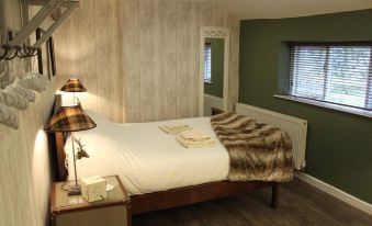 a cozy bedroom with a large bed , a nightstand , and a lamp on the floor at Beck Hall