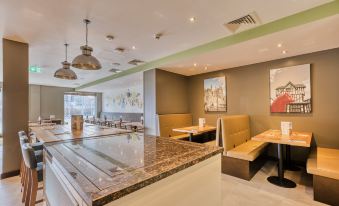 a modern restaurant with an open kitchen and dining area , featuring a long marble counter at Premier Inn Hereford City Centre (Old Market)