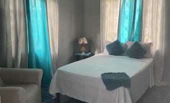 a bedroom with a white bed , blue curtains , and a couch , giving it a cozy and comfortable feel at Diamonds