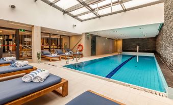 a large indoor swimming pool surrounded by lounge chairs , where people are relaxing and enjoying their time at Hilton Gdansk