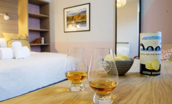 two glasses of whiskey are sitting on a table next to a bed in a hotel room at Lock Chambers, Caledonian Canal Centre