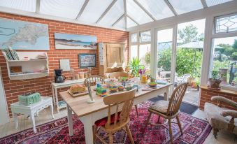 a dining room with a wooden table , chairs , and a brick wall , decorated with various items such as books , a vase , and a at Clarendon